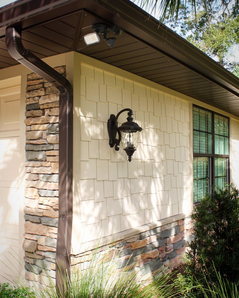 Exterior home renovation with decorative lighting and shake siding.